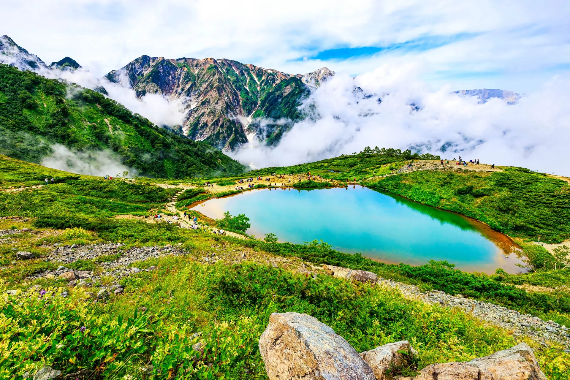 Summer trekking at Happo Pond — hikers with Northern Alps reflected in crystal-clear water